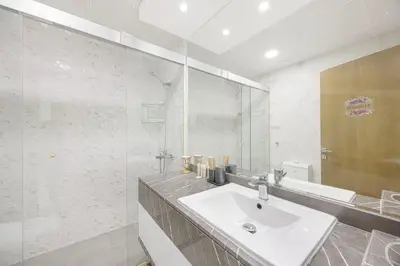 a white bathroom with a sink and a mirror at FiveX Premium 2BR with Extra Room in Dubai