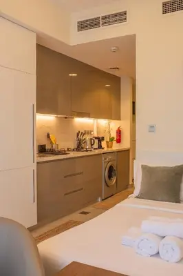 a bedroom with a white bed and a kitchen at Snug Modern Downtown Dubai Studio in Dubai
