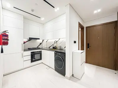 a kitchen with white cabinets and a washer and dryer at Modern Studio with Private Jacuzzi in Dubai