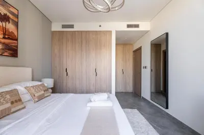 a bedroom with a large white bed and a chandelier at GuestReady - 1BR Luxury | Prime City Area in Dubai