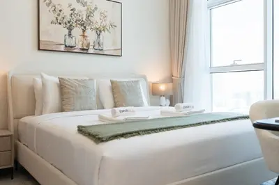a white bed in a room with a window at Luxury 1BR - Miracle Garden View - Skyz in Arjan in Dubai