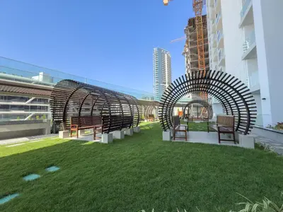 a group of chairs sitting on the grass near a building at Luxury 1BR - Miracle Garden View - Skyz in Arjan in Dubai