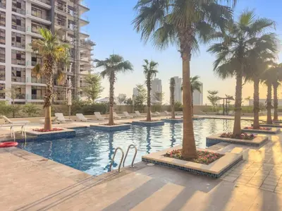 a swimming pool with palm trees and chairs in a building at FIRST CLASS Studio Cozy Luxe Retreat in Dubai