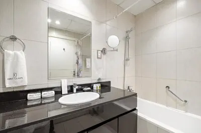 a bathroom with a sink and a mirror and a tub at FIRST CLASS Studio Cozy Luxe Retreat in Dubai