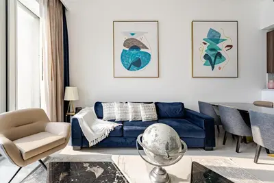 a living room with a blue couch and a table at Prestige Avani Residence 2BR with Golf Course View in Dubai