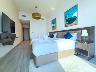 a bedroom with a large white bed and a television at Prestige Avani Residence 2BR with Golf Course View in Dubai