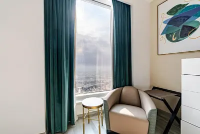 a living room with a couch and a large window at Prestige Avani Residence 2BR with Golf Course View in Dubai