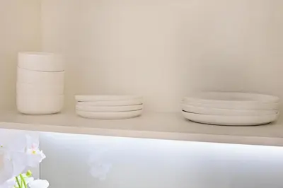 three white plates and bowls sitting on a shelf at Curated High Floor 1BR-Sofa Bed Water View Peninsula 1 in Dubai