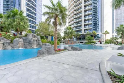 a swimming pool with palm trees and buildings at Amazing 1BR DAMAC Towers by Paramount in Dubai