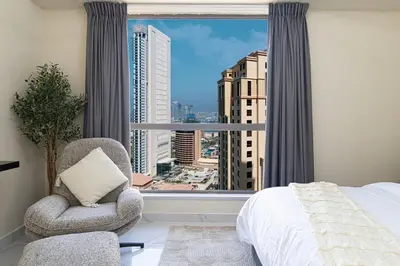 a bedroom with a bed and a chair and a large window at Beachfront Spacious Apartment with Sea & Palm Views in Dubai