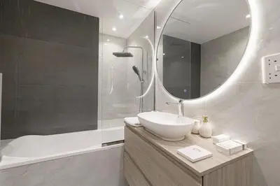 a bathroom with a sink and a mirror and a tub at Beachfront Spacious Apartment with Sea & Palm Views in Dubai