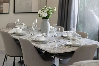 a table with chairs and a vase with flowers on it at Beachfront Spacious Apartment with Sea & Palm Views in Dubai