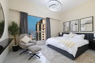 a bedroom with a bed and a chair and a window at Beachfront Spacious Apartment with Sea & Palm Views in Dubai
