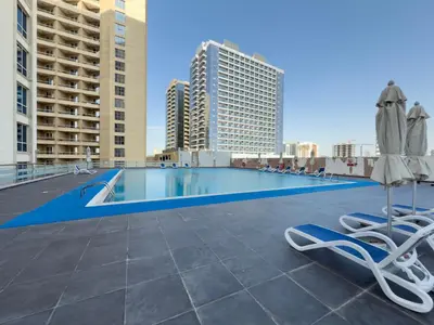 a swimming pool with chairs and umbrellas on a roof at Amazing View Studio Lago Vista IMPZ in Dubai