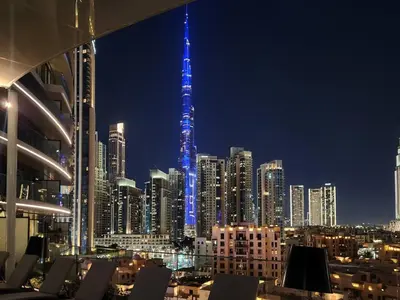a view of a city at night with a blue tower at Ultra-Luxury Apartment | Burj Khalifa Skyline Pool in Dubai