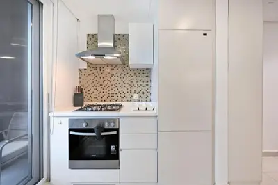 a white kitchen with a stove and a refrigerator at Bloomfields Luxury 1BR, Damac Voleo, Business Bay in Dubai