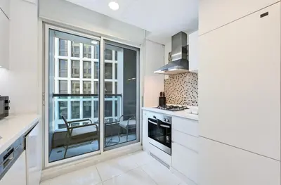 a kitchen with white cabinets and a large window at Bloomfields Luxury 1BR, Damac Voleo, Business Bay in Dubai