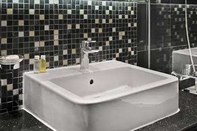 a white sink in a bathroom with black tiles at Bloomfields Luxury 1BR, Damac Voleo, Business Bay in Dubai