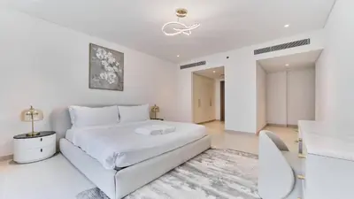 a white bedroom with a white bed and a table at Contemporary 2BR in Central Park Viridian in Dubai
