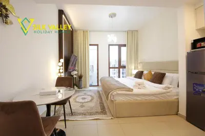 a bedroom with a bed and a table in it at Silk Valley - Luxury Studio with Pool View - Walk to Park in Dubai