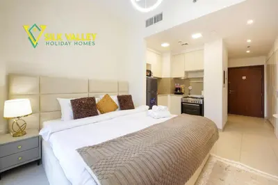 a bedroom with a large bed and a kitchen at Silk Valley - Luxury Studio with Pool View - Walk to Park in Dubai