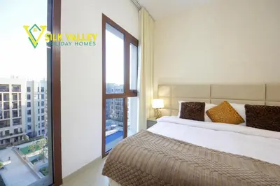a bedroom with a bed and a large window at Silk Valley - Luxury Studio with Pool View - Walk to Park in Dubai