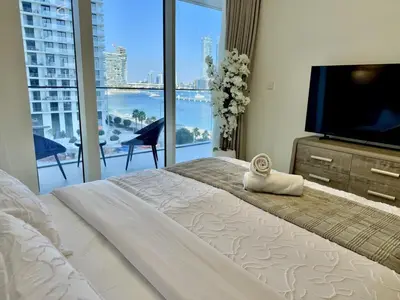 a bedroom with a large bed with a flat screen tv at BRAND NEW 2 BDR apartment with beach access in Dubai