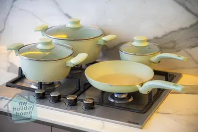 three pots and pans sitting on top of a stove at Modern 1BR Azizi Riviera with Pool & Gym in Dubai