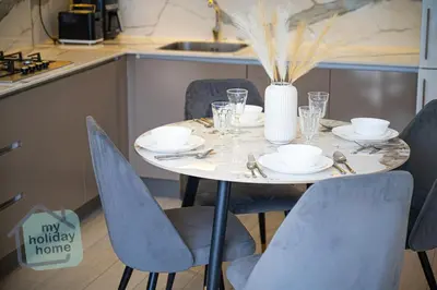 a table in a kitchen with a vase and chairs at Modern 1BR Azizi Riviera with Pool & Gym in Dubai