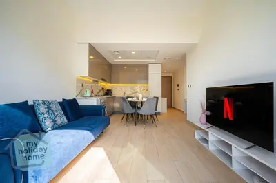 a living room with a blue couch and a tv at Modern 1BR Azizi Riviera with Pool & Gym in Dubai