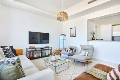 a living room with a couch and chairs and a tv at Frank Porter - Mada Residences in Dubai