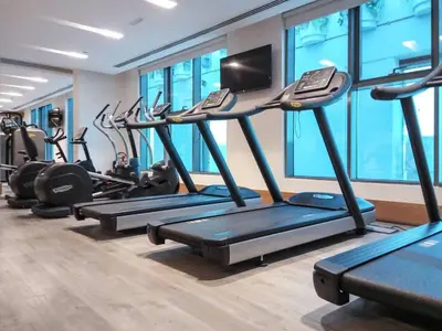 a gym with rows of treadmills and a television at Frank Porter - Mada Residences in Dubai