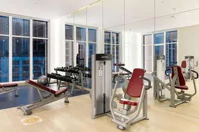 a gym with cardio equipment in a building with windows at Modern Studio in Business Bay - Canal & City Views - Gym & Pool in Dubai