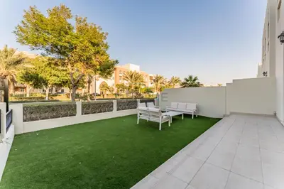 an apartment patio with a green lawn at Spacious 3BR and Assistant Room with Community View - Al Quortaj Villa, Al Furjan by Deluxe Holiday Homes in Dubai