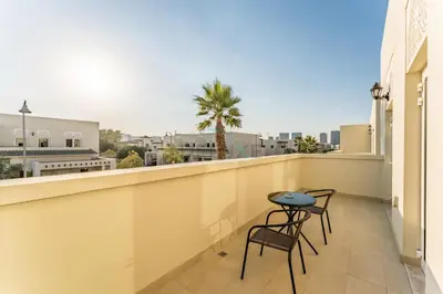 a balcony with two chairs and a table on it at Spacious 3BR and Assistant Room with Community View - Al Quortaj Villa, Al Furjan by Deluxe Holiday Homes in Dubai