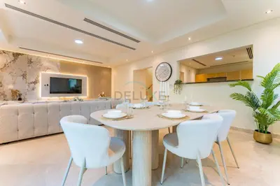 a dining room with a table and white chairs at Spacious 3BR and Assistant Room with Community View - Al Quortaj Villa, Al Furjan by Deluxe Holiday Homes in Dubai