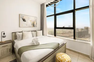 a bedroom with a large bed with a large window at Relaxing Studio with Balcony & Pool at The Square Tower in Dubai