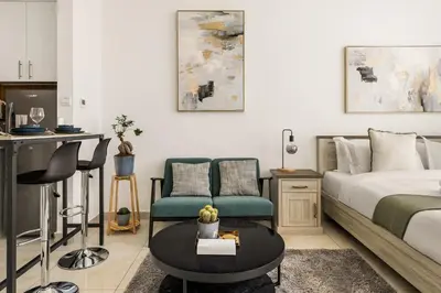 a bedroom with a bed and a chair and a table at Relaxing Studio with Balcony & Pool at The Square Tower in Dubai