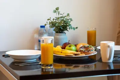 a table with a plate of fruit and orange juice at DAMAC COUR JARDIN - Near Metro - Free Parking in Dubai