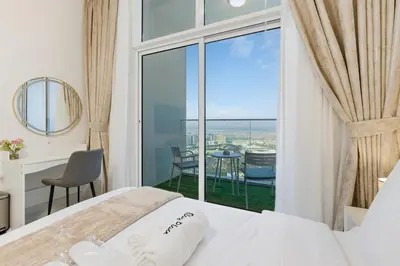 a bedroom with a bed and a view of the ocean at Modern Studio on 27th Floor with Miracle Garden Views in Dubai
