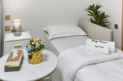 two beds in a room with a table with a pillow and flowers at Modern Studio on 27th Floor with Miracle Garden Views in Dubai