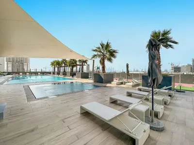 a swimming pool with lounge chairs and a umbrella at Spacious Studio w Sofa Bed Sleeps 4 in JVC in Dubai