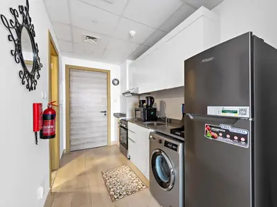 a kitchen with a stainless steel refrigerator and a dishwasher at Spacious Studio w Sofa Bed Sleeps 4 in JVC in Dubai