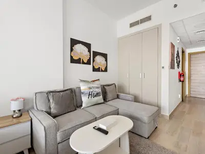 a living room with a couch and a table at Spacious Studio w Sofa Bed Sleeps 4 in JVC in Dubai