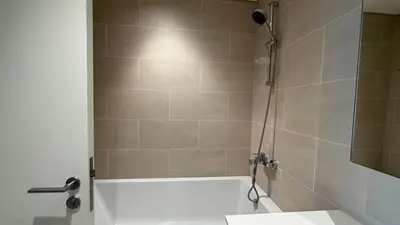 a bathroom with a shower with a white bath tub at Luxury 2BR in Creek Beach with Lagoon Access in Dubai