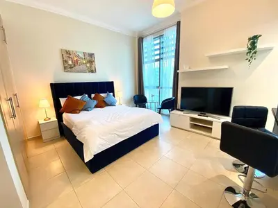 a bedroom with a bed and a flat screen tv at Stylish Studio near the beach in Dubai Marina in Dubai