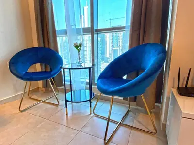 two blue chairs and a table in front of a window at Stylish Studio near the beach in Dubai Marina in Dubai