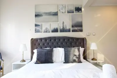 a bedroom with a bed with white sheets and pictures on the wall at Enjoy Studio in Dubai Marina - Partial Marina View in Dubai