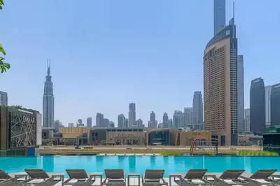 a swimming pool with chairs and a city skyline at Vogue Downtown Views II with Direct Access to Dubai Mall Via a Climate Controlled Bridge, One Bedroom Apartment with Balcony and City View in Dubai