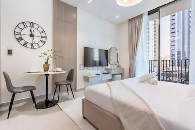 a bedroom with a bed and a table and a clock at Prime Location, Walking Distance to Circle Mall, Minutes Drive from Dubai Marina and Palm Jumeirah - Binghatti Aurora, JVC by Deluxe Holiday Homes in Dubai